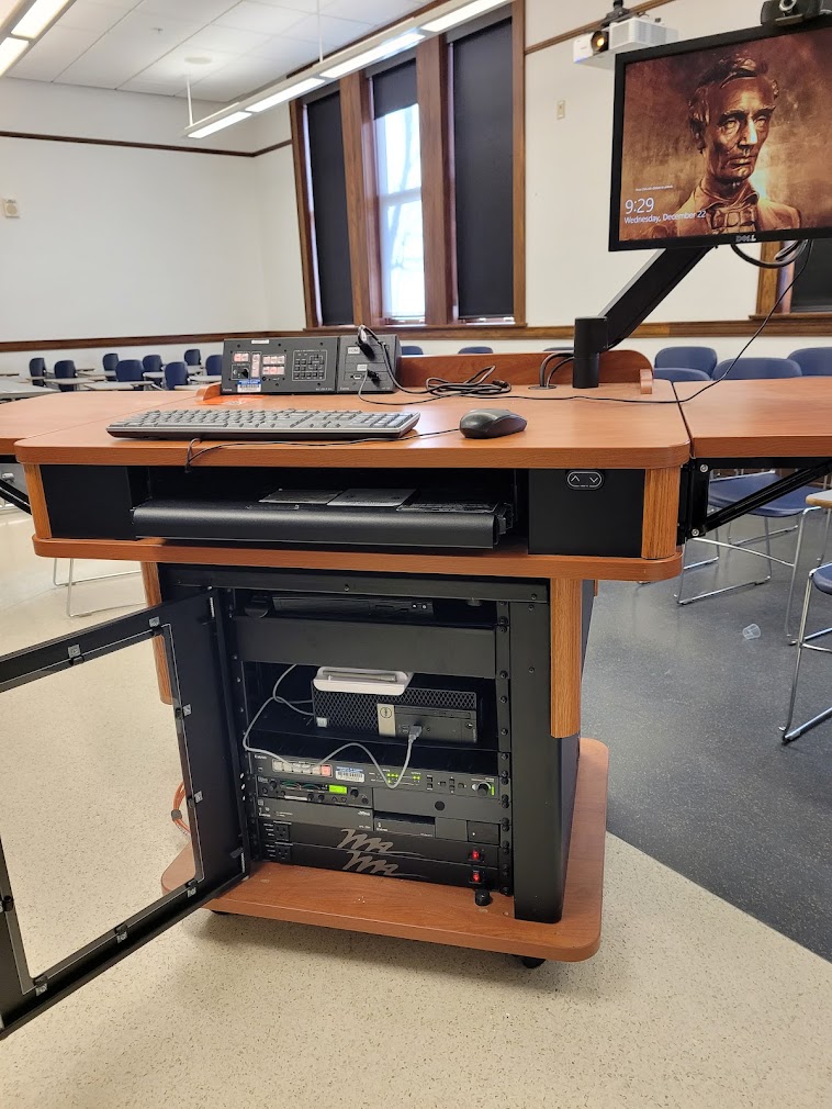 A view of the open cabinet with a computer monitor, HDMI input, a push button controller, and audio visual rack.