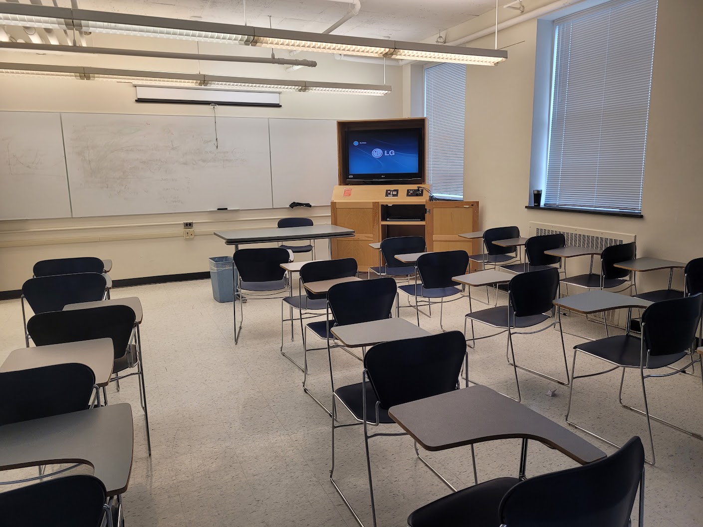 A view of the classroom with movable tableted arm chairs, white board, and instructor station in front.
