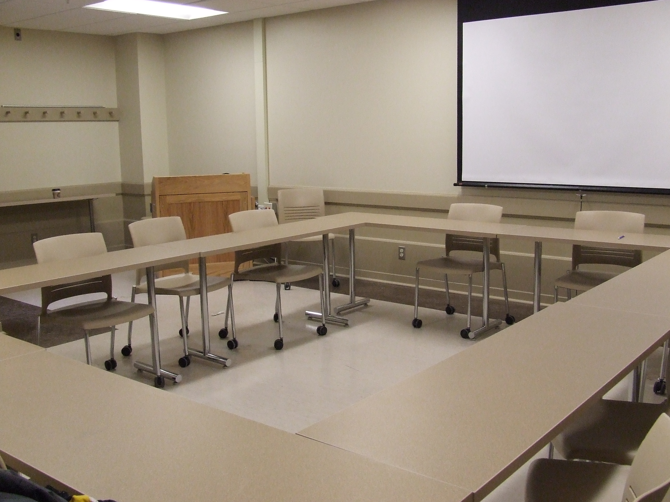 A view of the classroom with movable tables and chairs and instructor table in front.