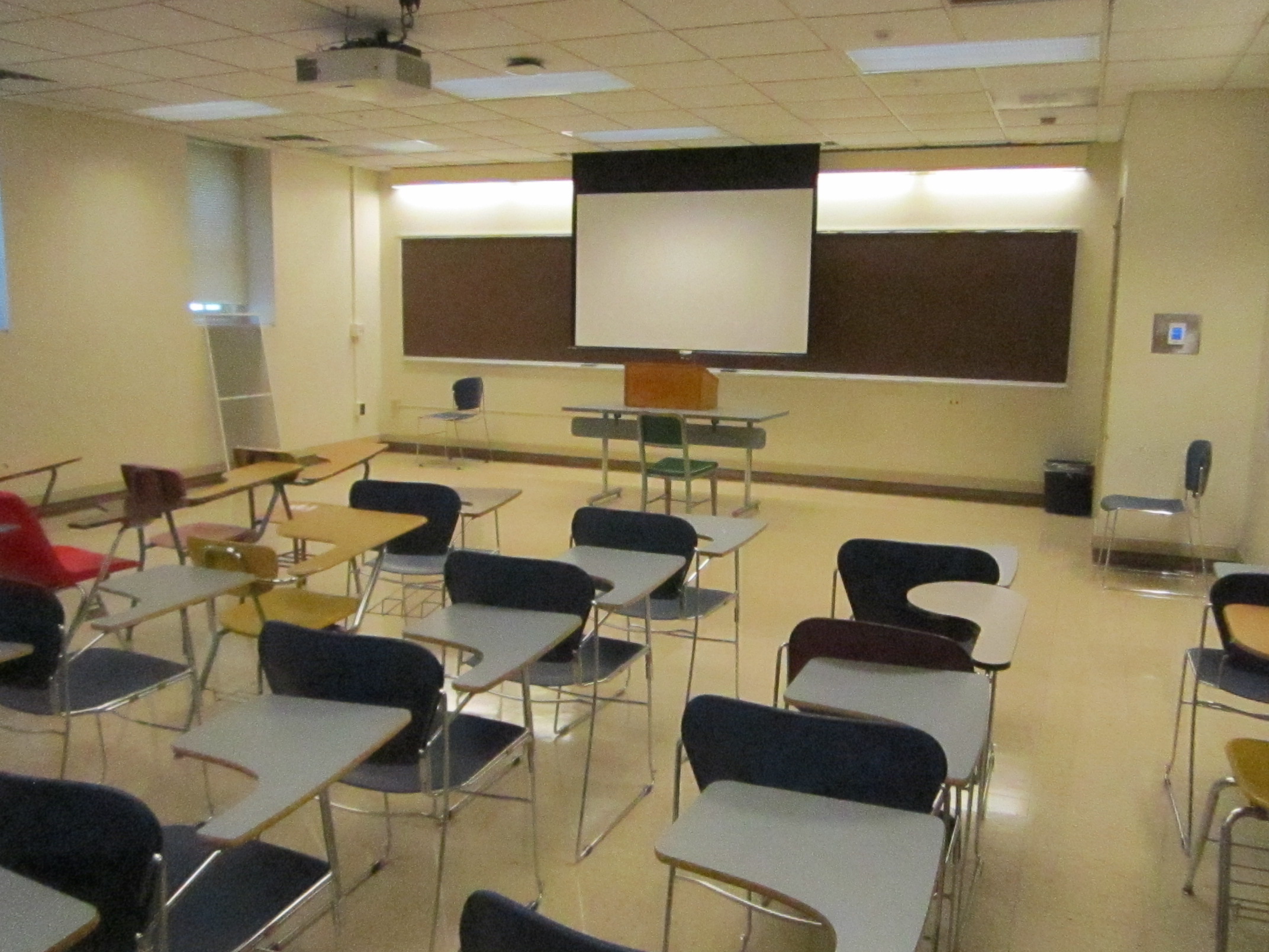 This is a view of the room, with student desks, a front lecture table, and a chalkboard.