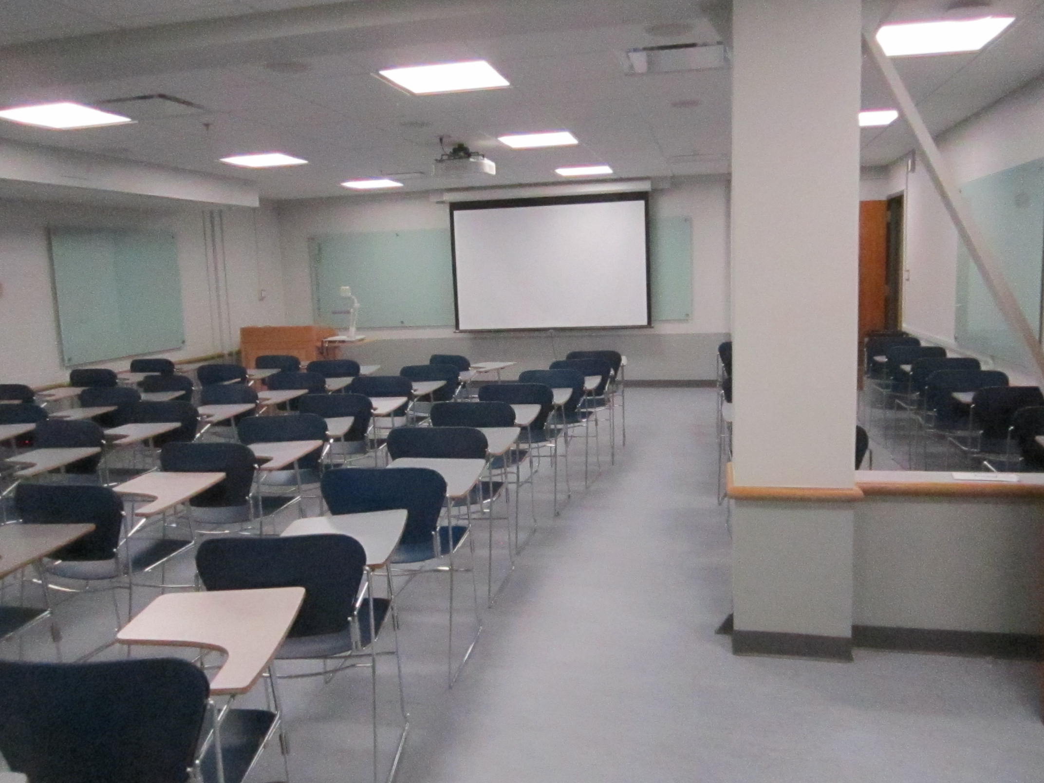 A view of the classroom with movable tablet arm chairs and whiteboards in front.