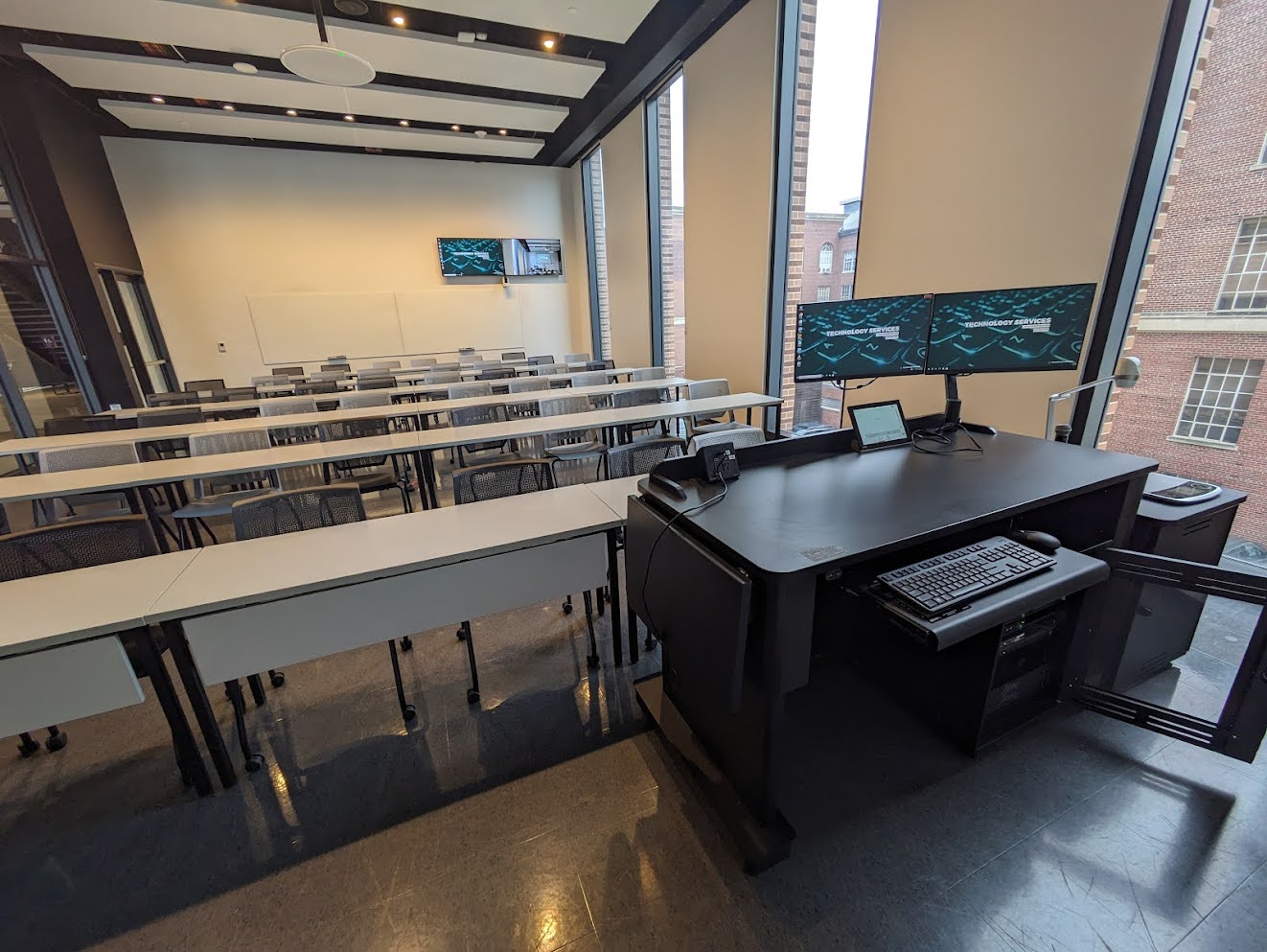 This is a view of the room, with student desks, a front lecture table, and white boards.