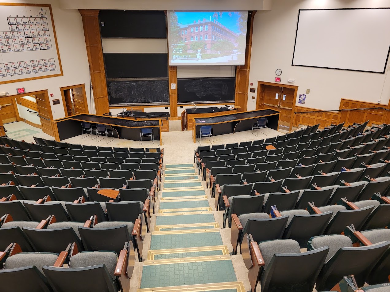 A view of the classroom with theater auditorium seating, chalkboards, and instructor laboratory table in front.