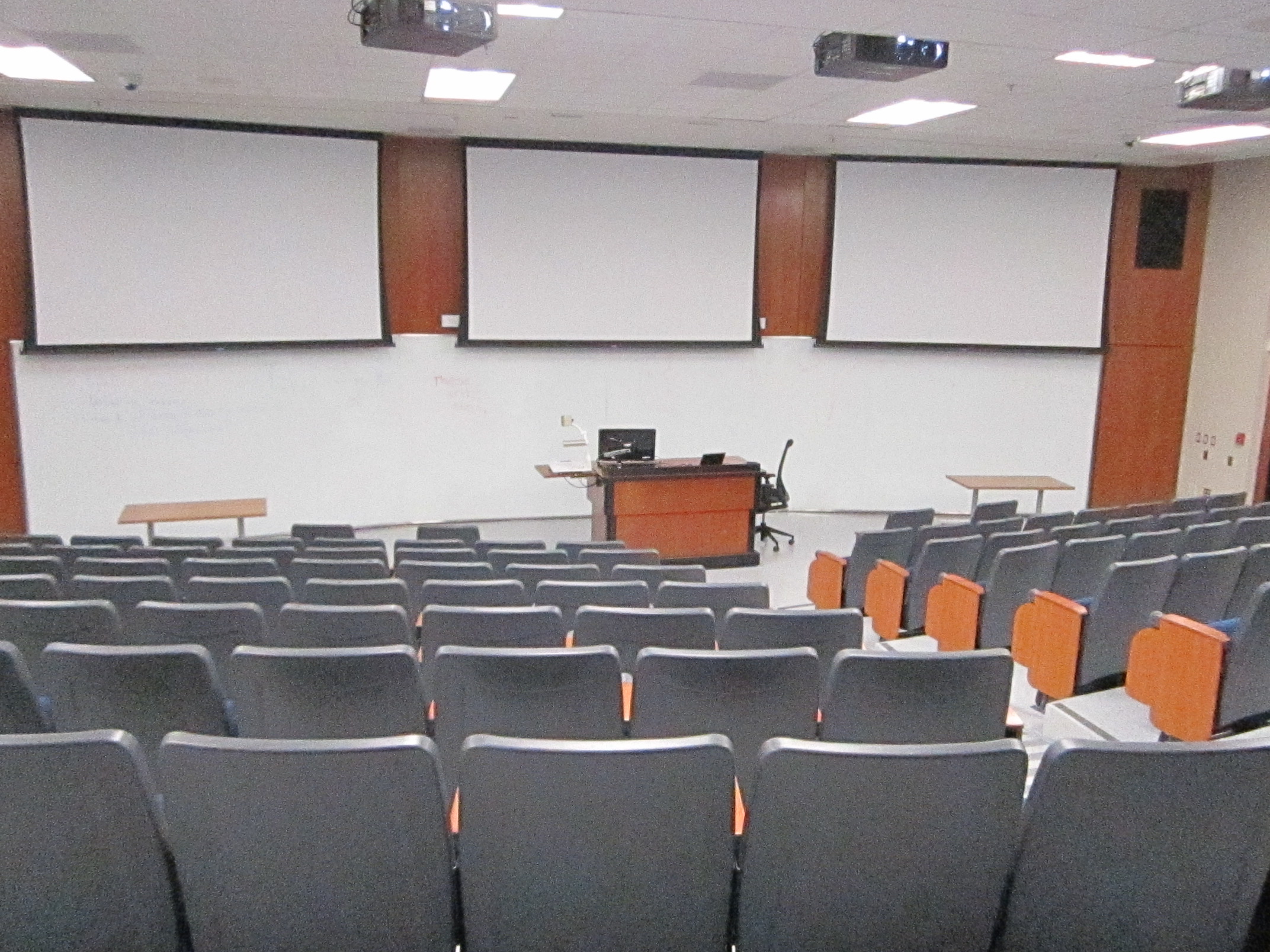 A view of the classroom with theater seating, whiteboard, and instructor table in front.