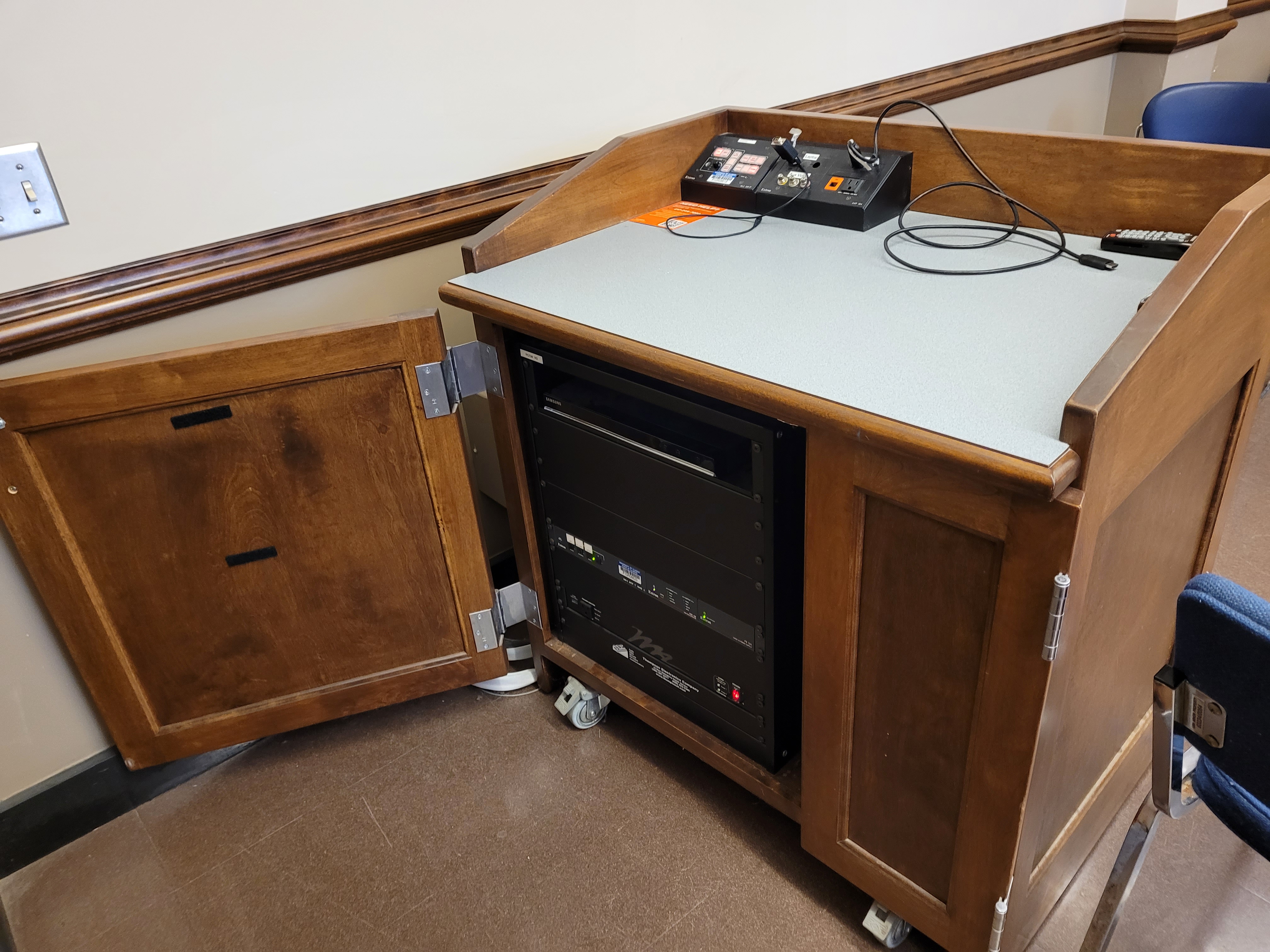 A view of the open cabinet with VGA and HDMI inputs, push button controller, and audio visual rack.