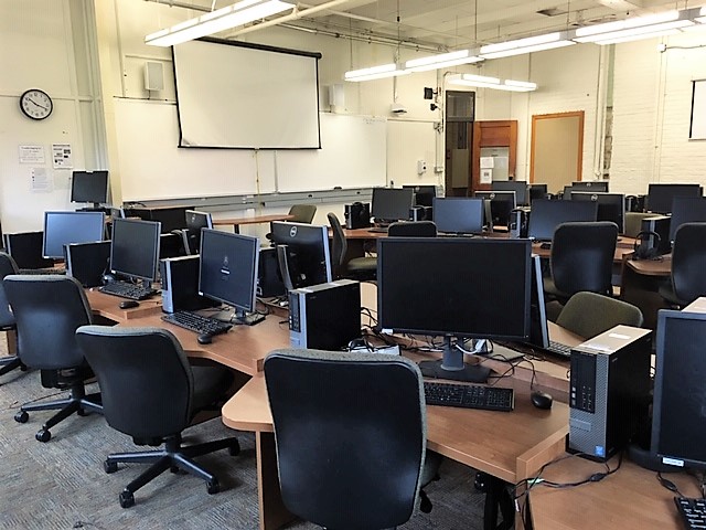 This is a view of the room, with student desks, a front lecture table, and white boards.