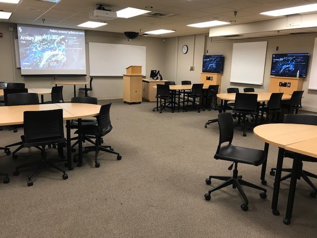 This is a view of the room, with student desks, a front lecture table, and a whiteboard.