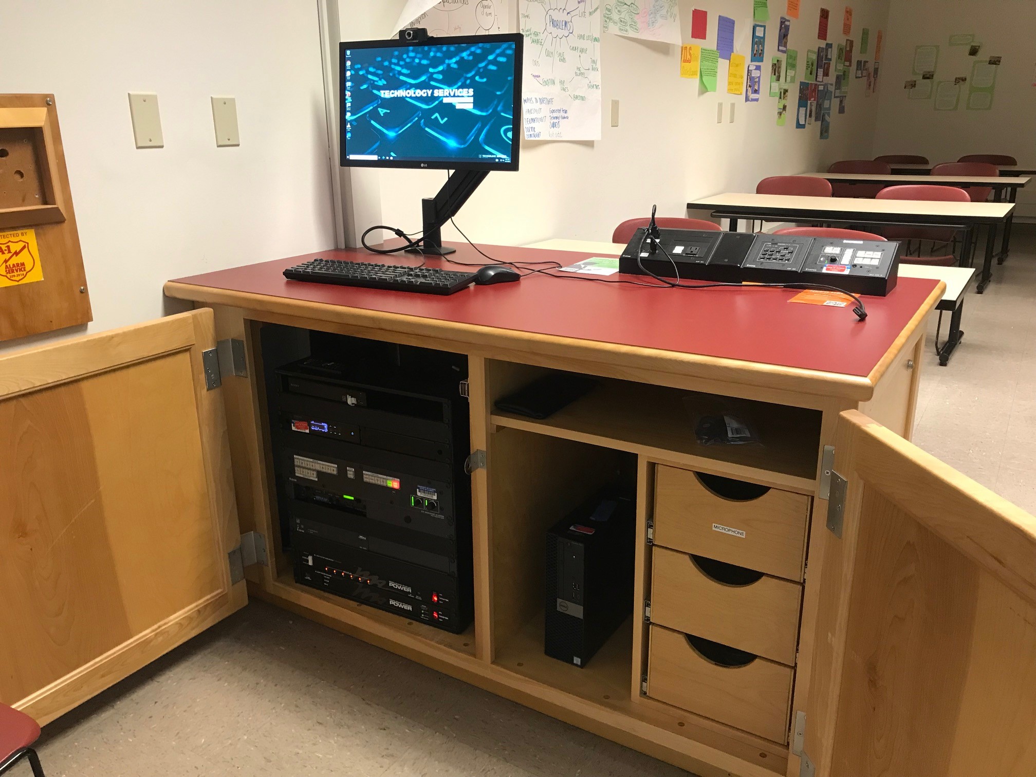 A view of the open cabinet with a computer monitor, resident computer, HDMI input, Blu-ray player, push button controller, and audio visual rack.