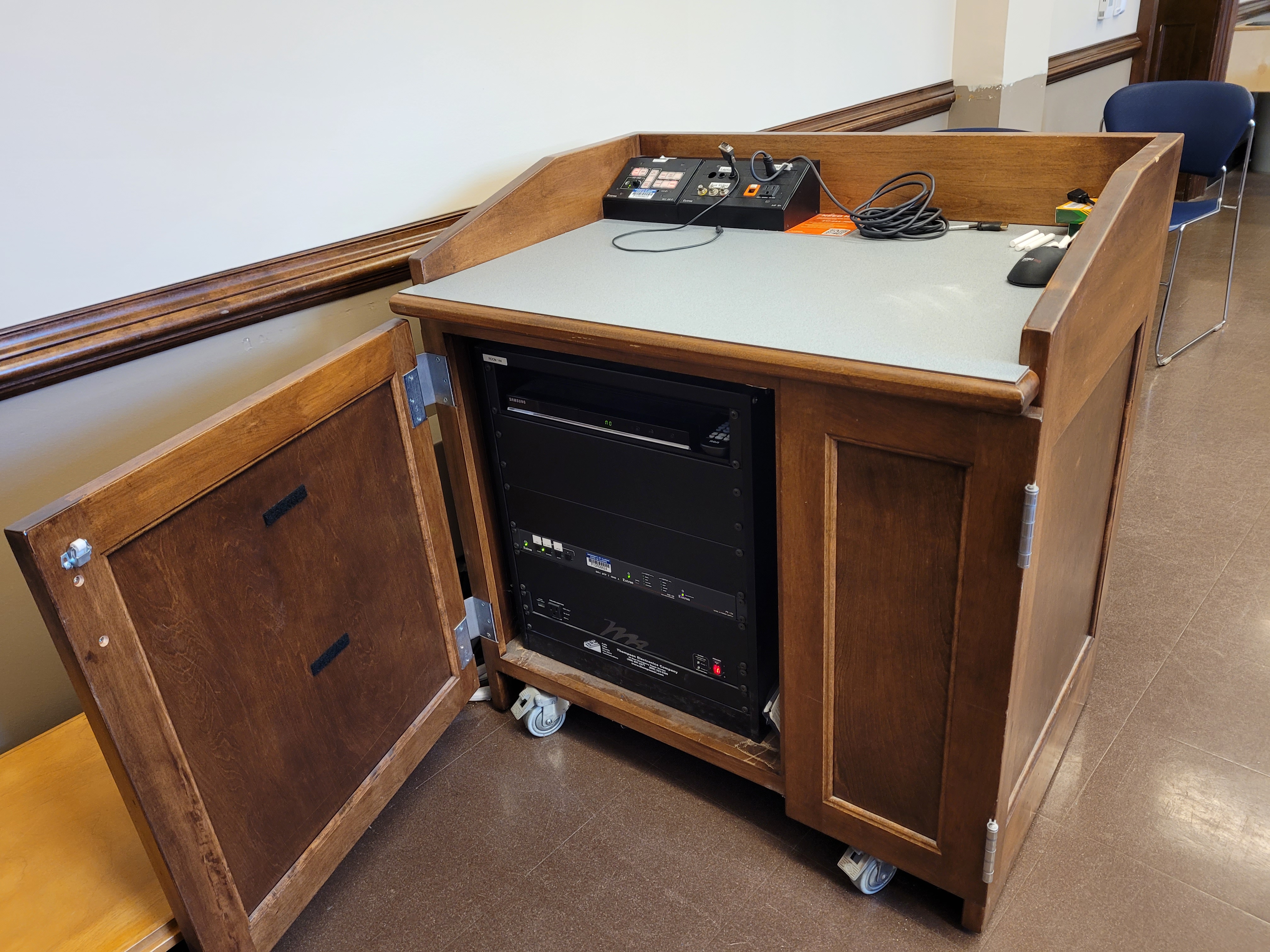 A view of the open cabinet with  HDMI input, a push button controller, and audio visual rack