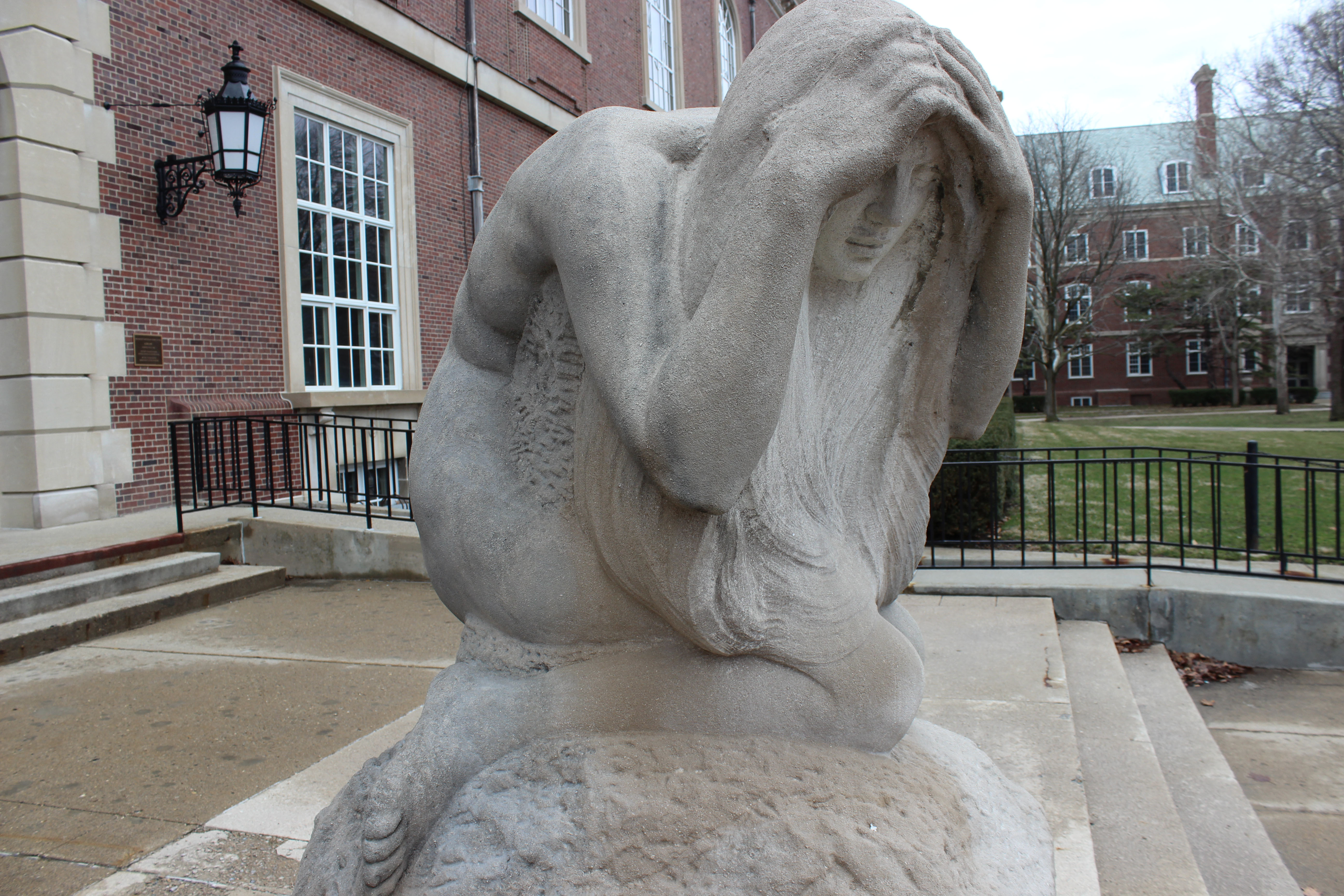 Statue of a person with hands over face. Located by the Main Library entrance facing the UGL 
