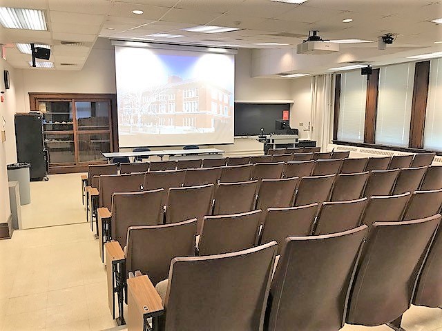 A view of the classroom with theater auditorium seating and instructor table in front.