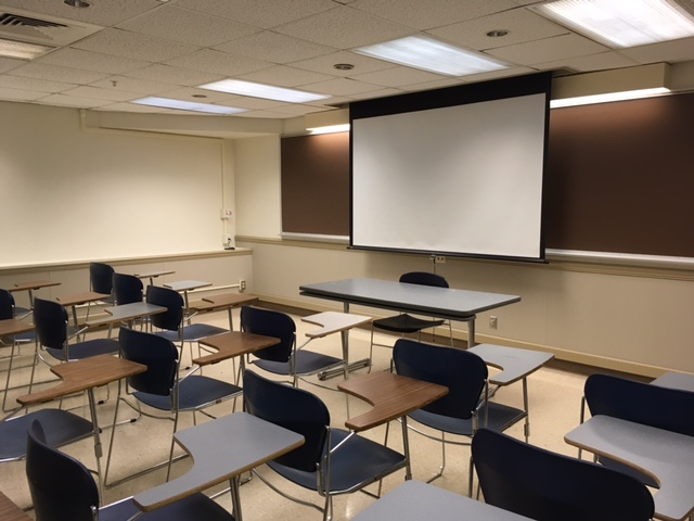 This is a view of the room, with student desks, a front lecture table, and a chalkboard.