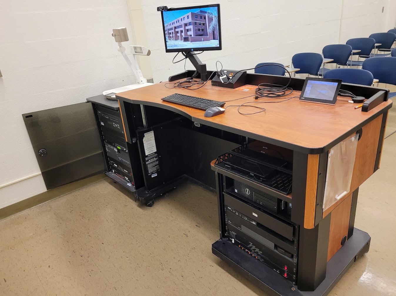 A view of the open cabinet with a computer monitor, VGA and HDMI inputus, a touch panel controller, document camera, and audiovisual rack.