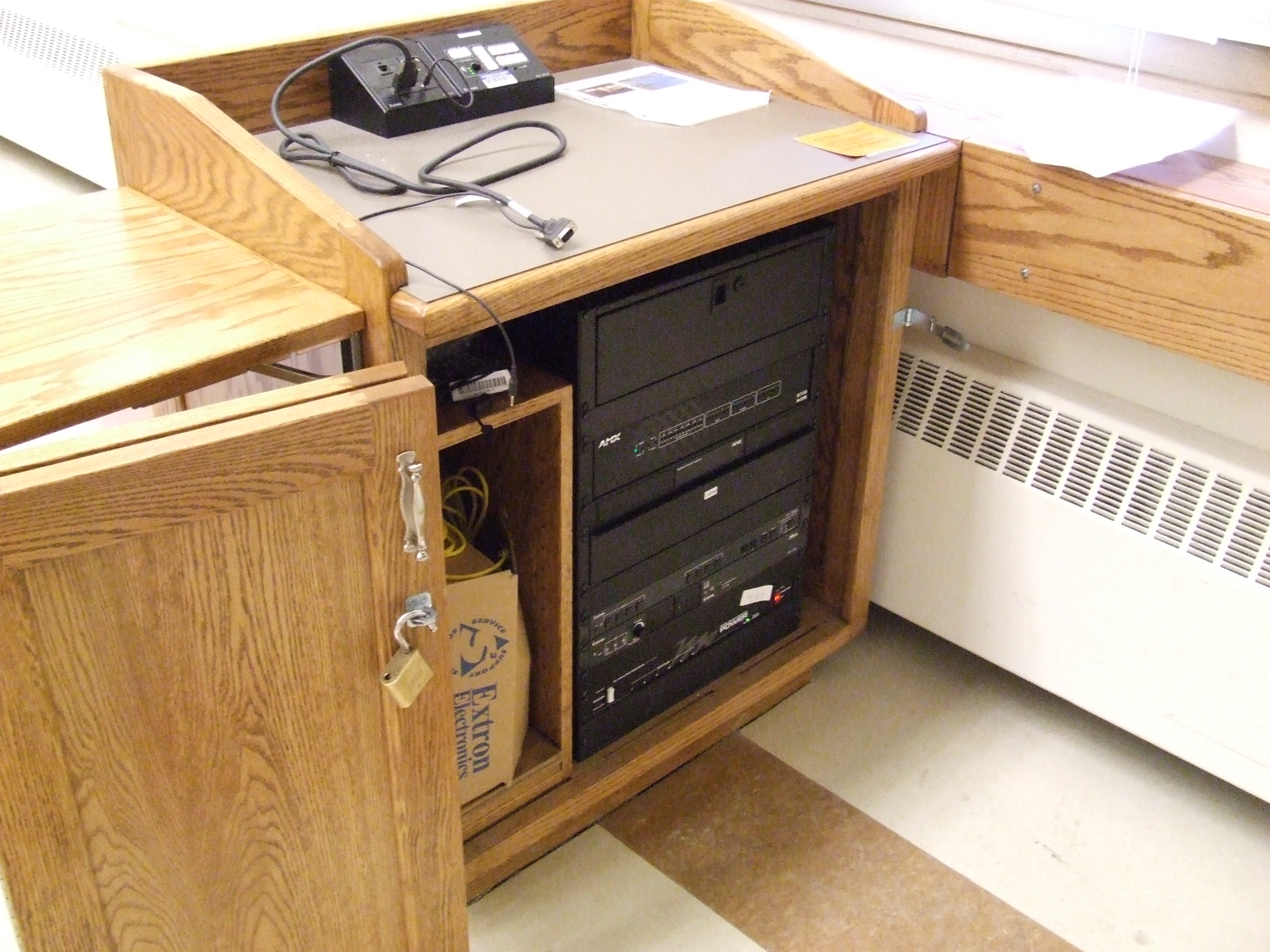 A view of the open cabinet with HDMI input, a push button controller, and audio visual rack.