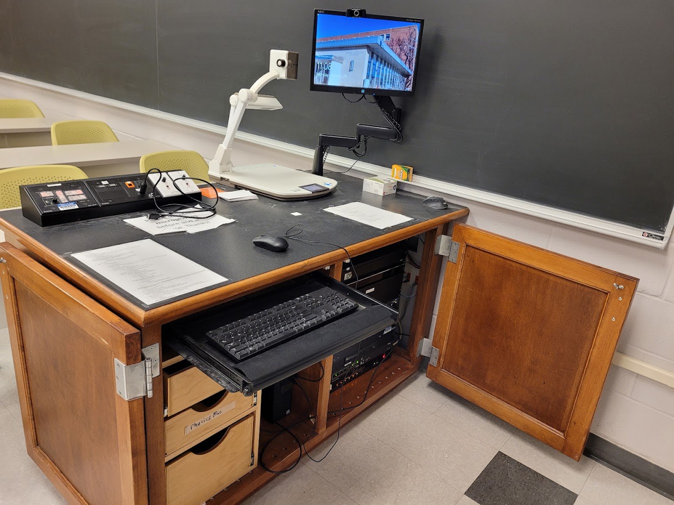 A view of the open cabinet with a computer monitor, HDMI input, a push button controller, document camera, and audio visual rack.