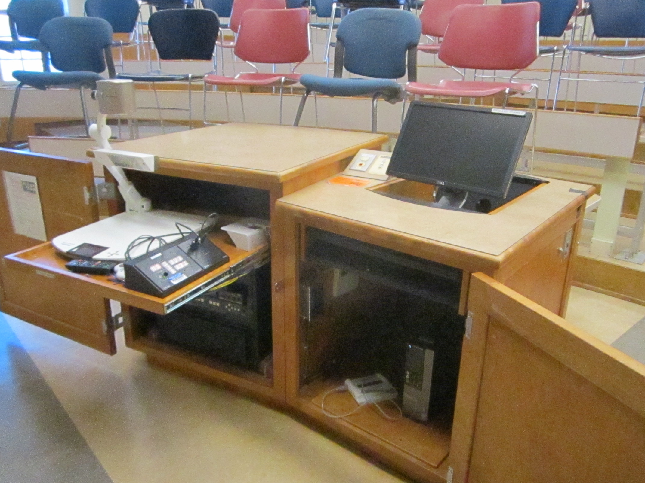 A view of the open cabinet with a computer monitor, VGA and HDMI inputs, document camera, a push button controller, audio visual rack, and electric screen controls.