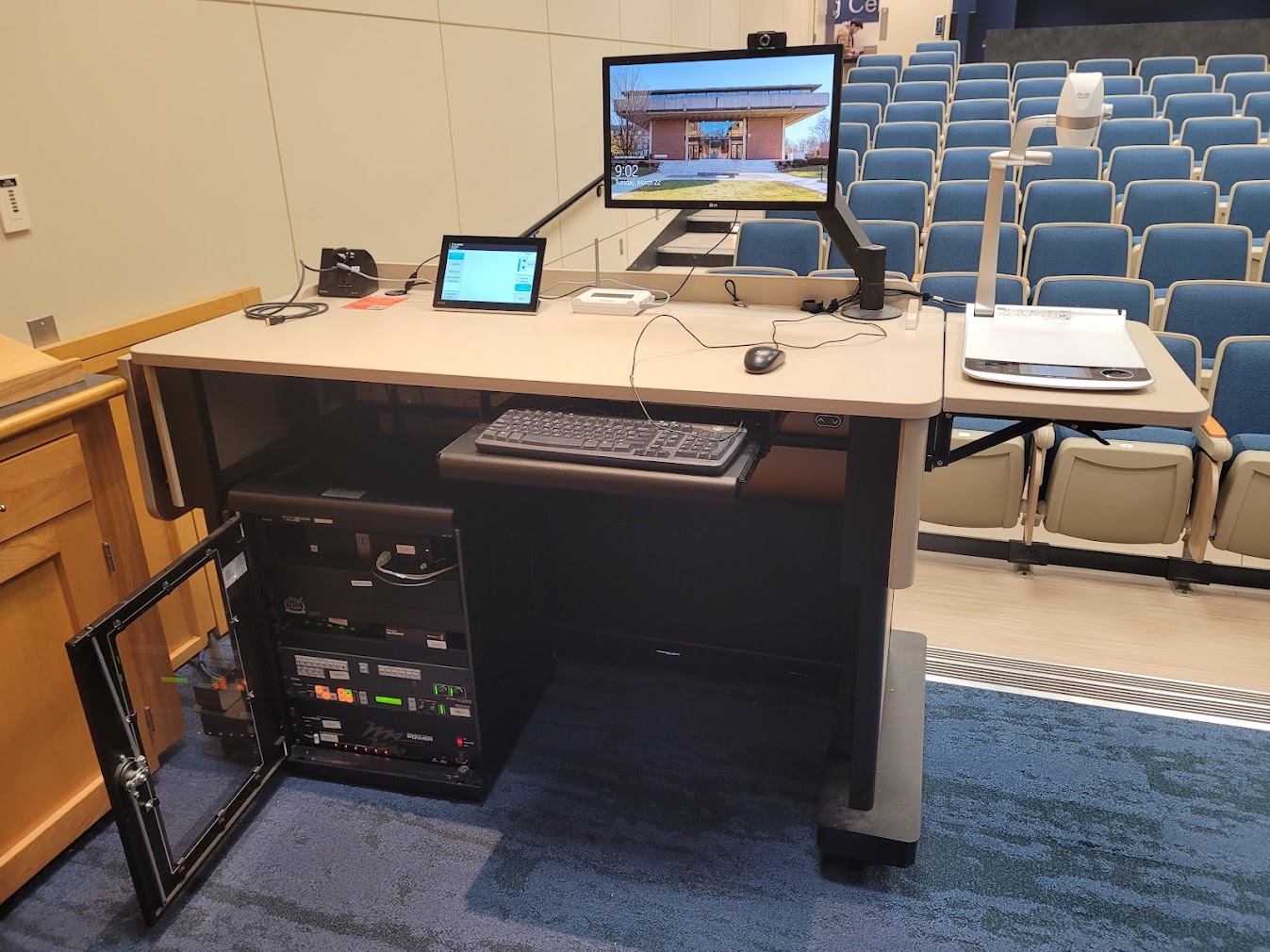 A view of the open cabinet with a computer monitor, HDMI input, a touch panel controller, document camera, audio visual rack and electric screen controls.