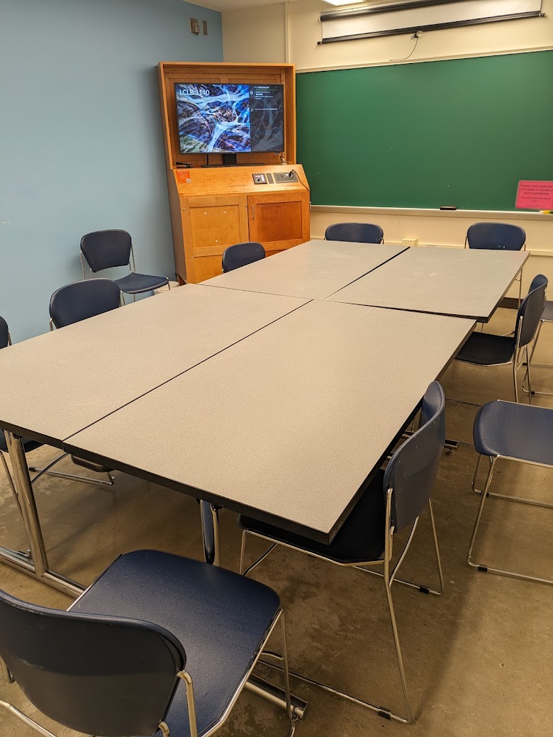 A view of the classroom with movable tables and chairs, and a chalkboard