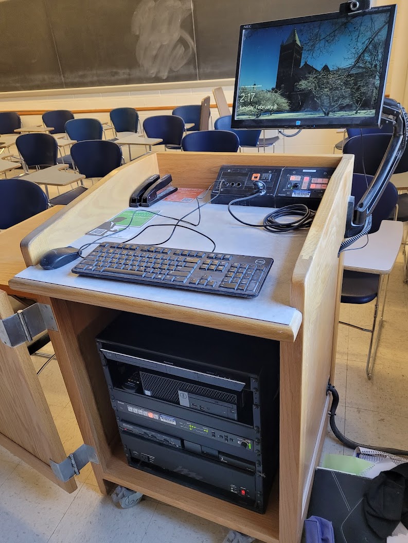 A view of the open cabinet, a computer monitor, HDMI input, a push button controller and audiovisual rack.