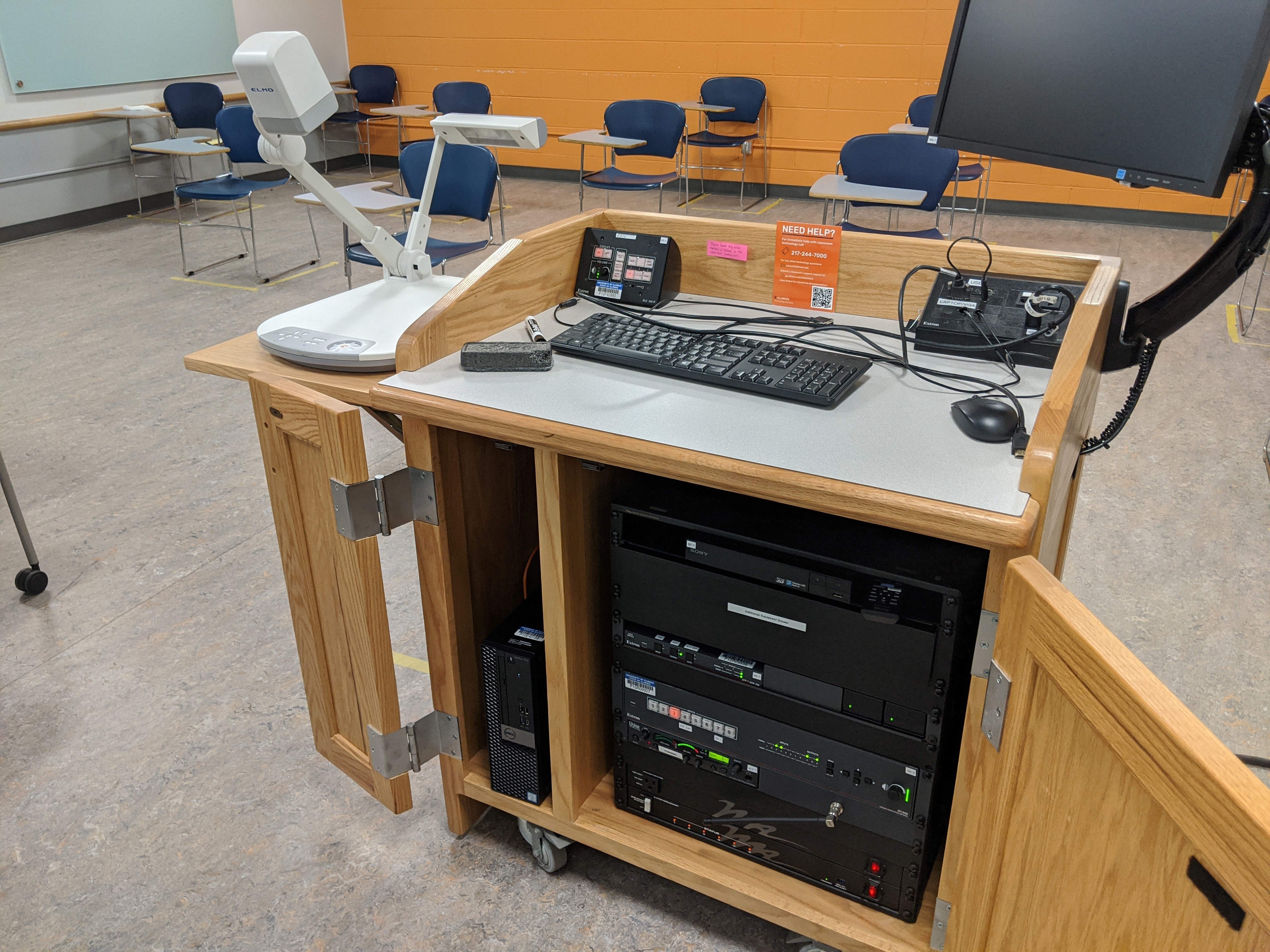 A view of the open cabinet with a PC, Document Camera, and HDMI inputs, a push button controller, and audio visual rack.