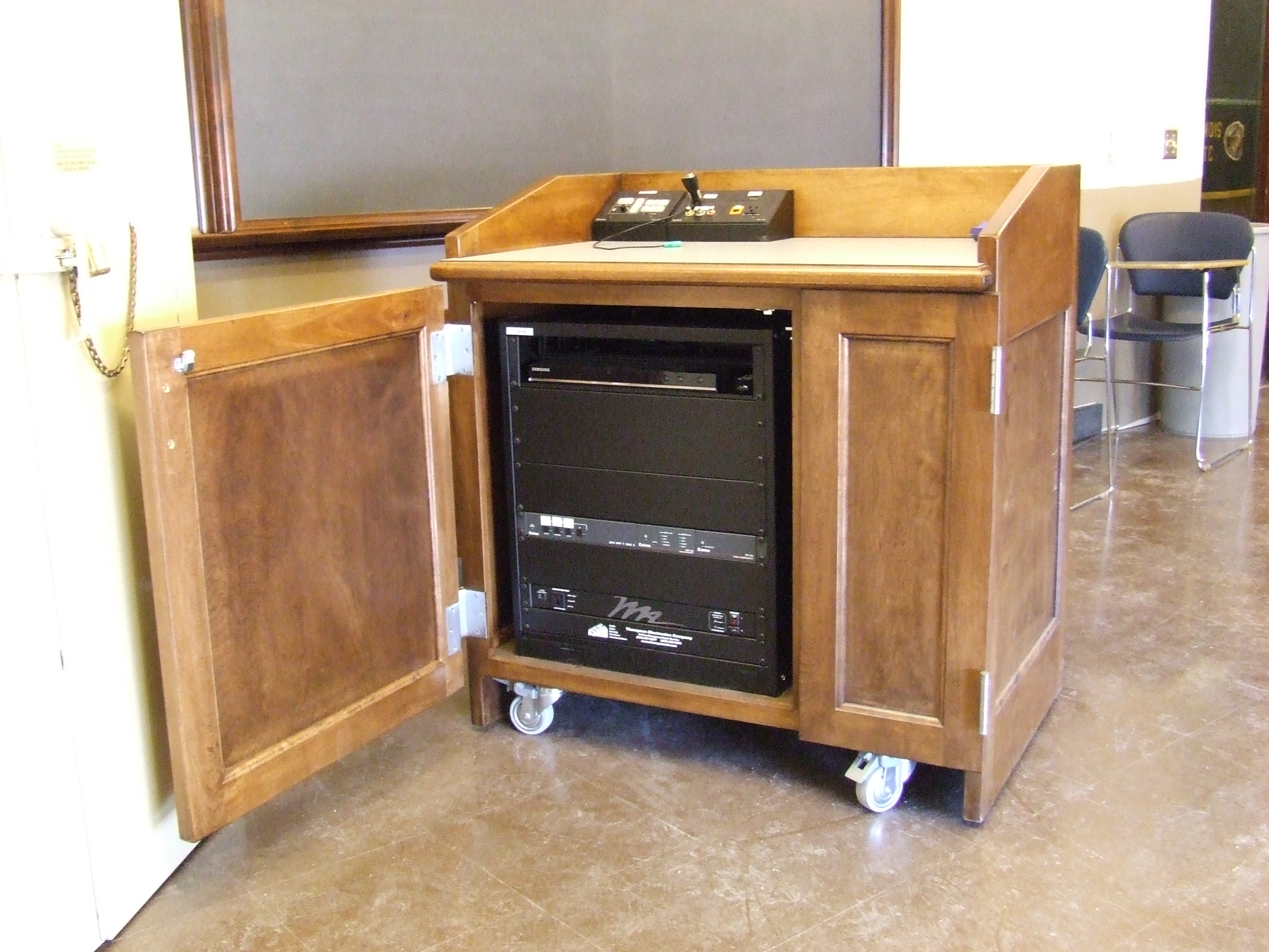 A view of the open cabinet with HDMI inputs, a push button controller, and audio visual rack.