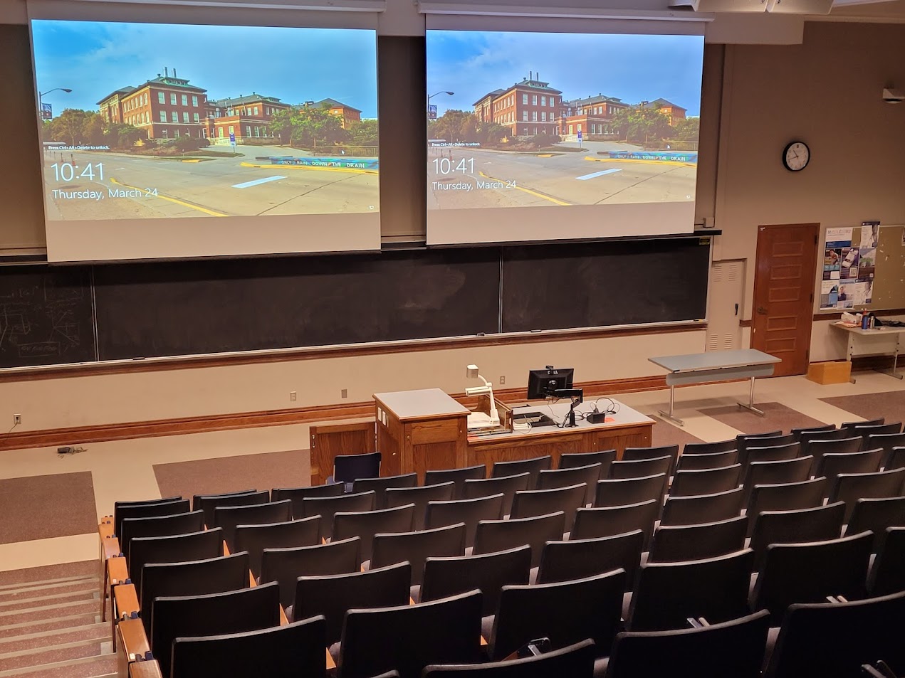 A view of the classroom with Theatre Auditorium seating, chalkboard, and instructor table in front