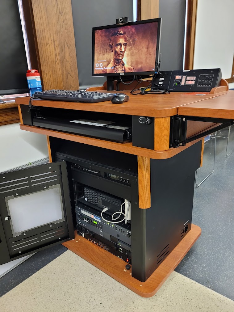 A view of the open cabinet with a computer monitor, HDMI input, a push button controller, and audiovisual rack.