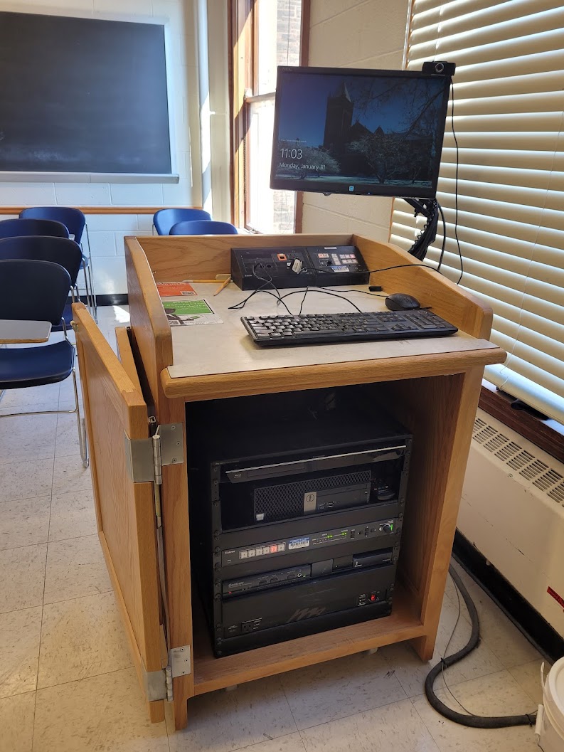 A view of the cabinet with a computer monitor, HDMI inputs, a push button controller, and audio visual rack.
