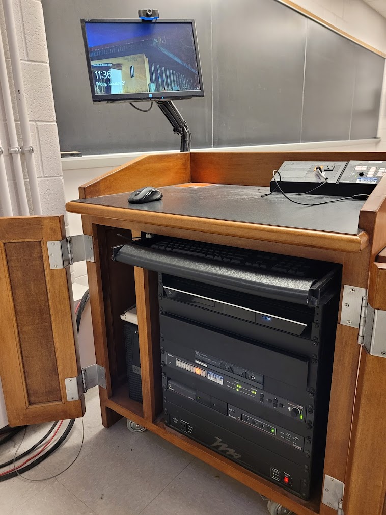 A view of the open cabinet with a computer monitor, HDMI inputs, a push button controller, and audio visual rack.
