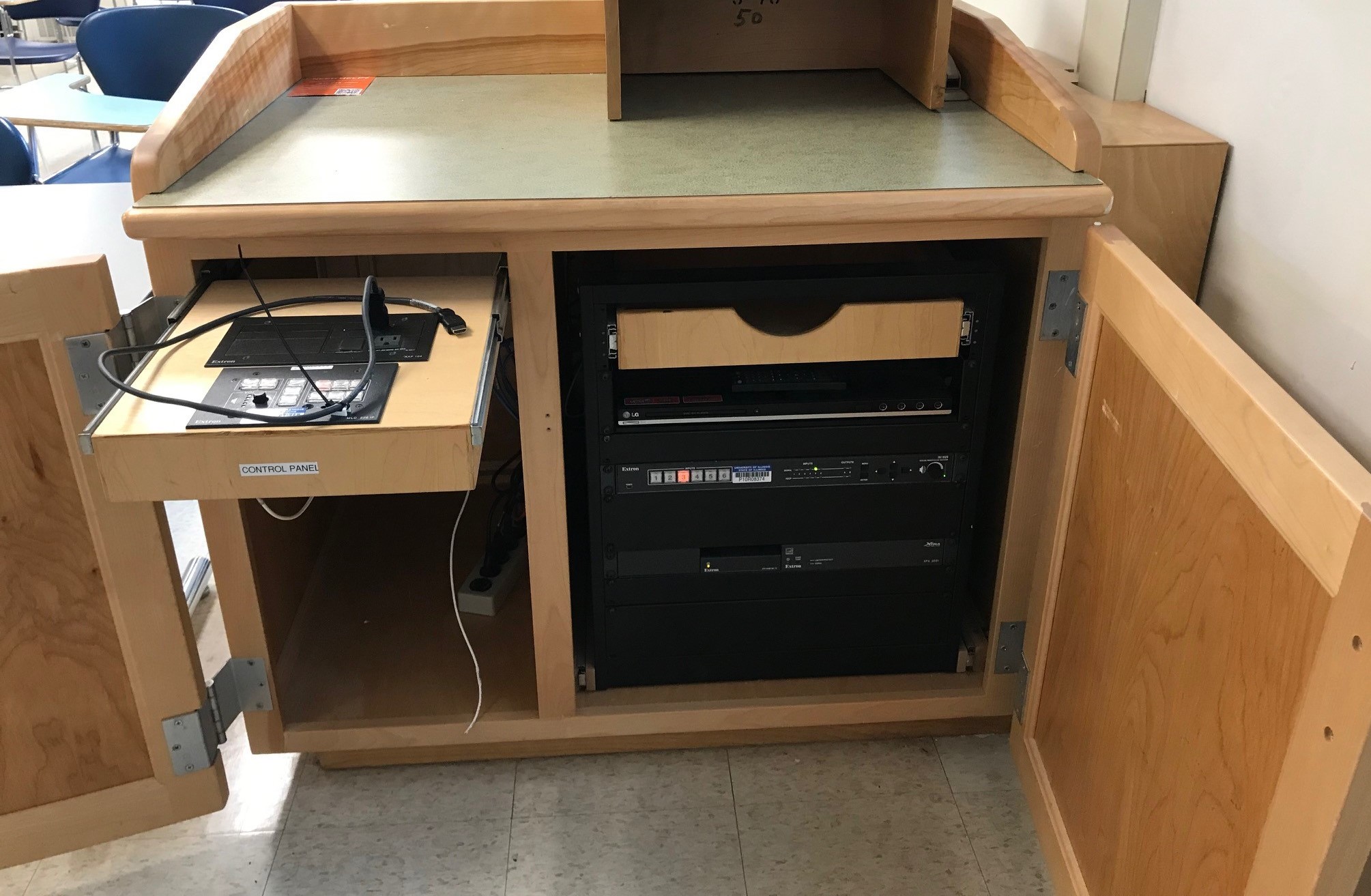 A view of the open cabinet with HDMI input, push button controller, and audio visual rack.
