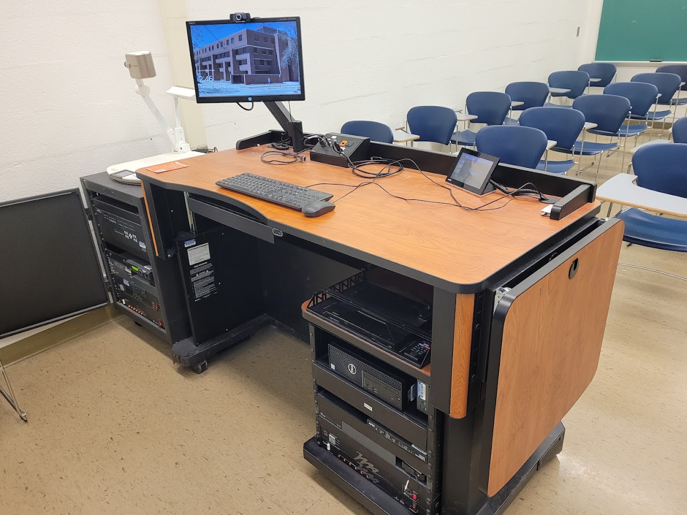 A view of the open cabinet with a computer monitor, VGA and HDMI inputs, a touch panel controller, document camera, and audiovisual rack.