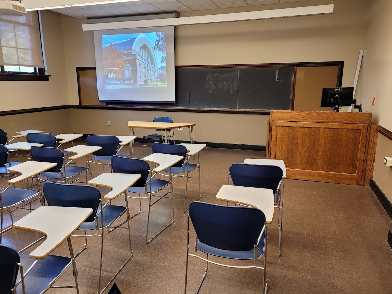 A view of the classroom with movable tableted arm chairs and instructor table in front.