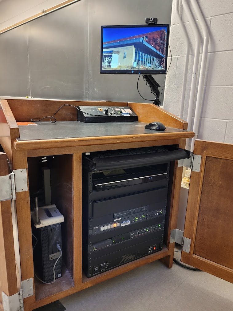A view of the open cabinet with a computer monitor, HDMI inputs, a push button controller, and audio visual rack.
