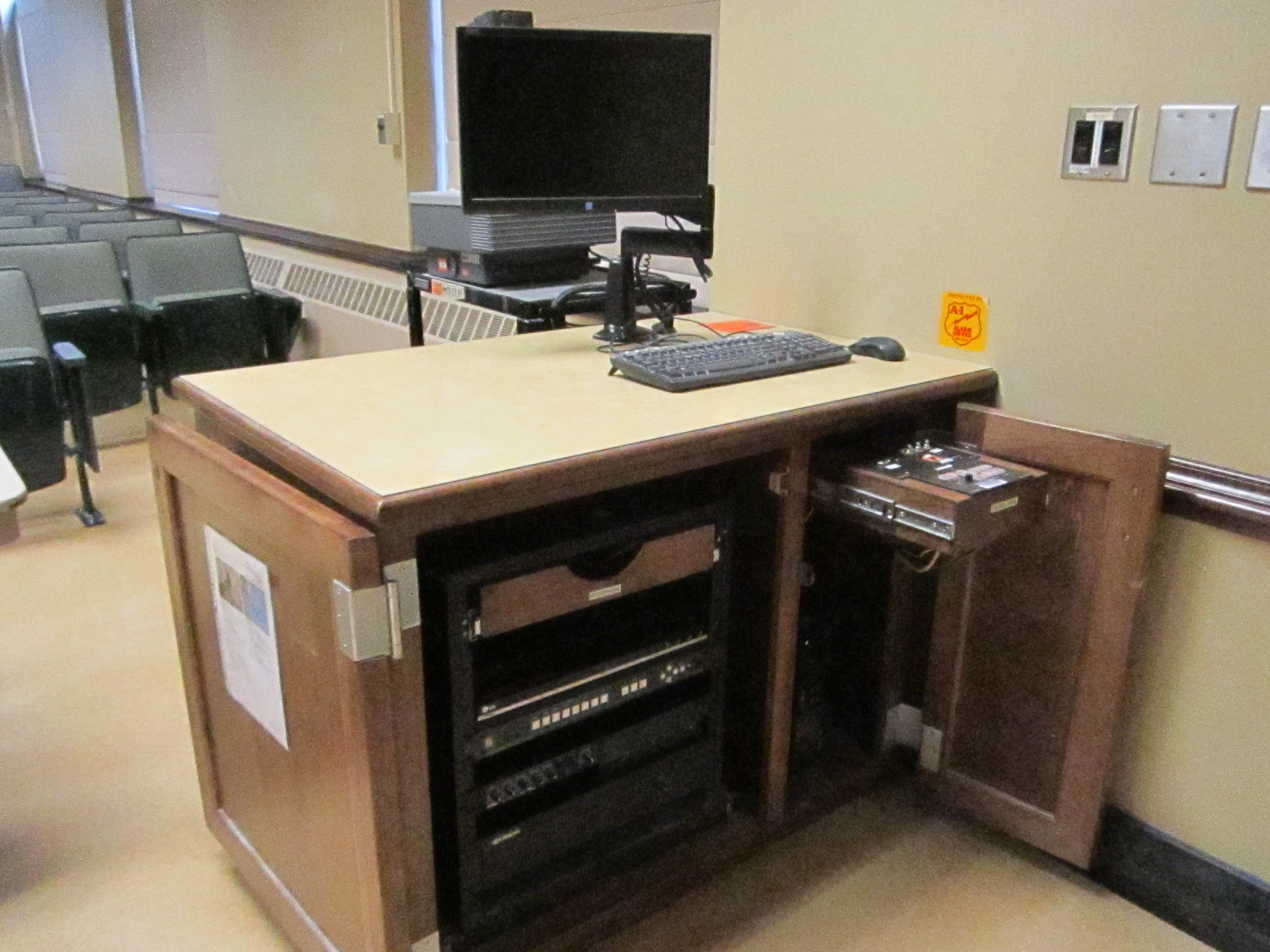 A view of the open cabinet with a computer monitor, HDMI inputs, a push button controller, and audio visual rack