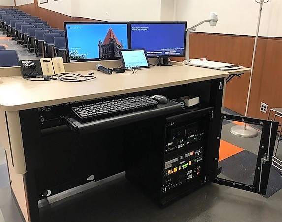 A view of the open cabinet with a computer monitor, HDMI inputs, a touch panel controller, document camera, audio visual rack, and electric screen control.