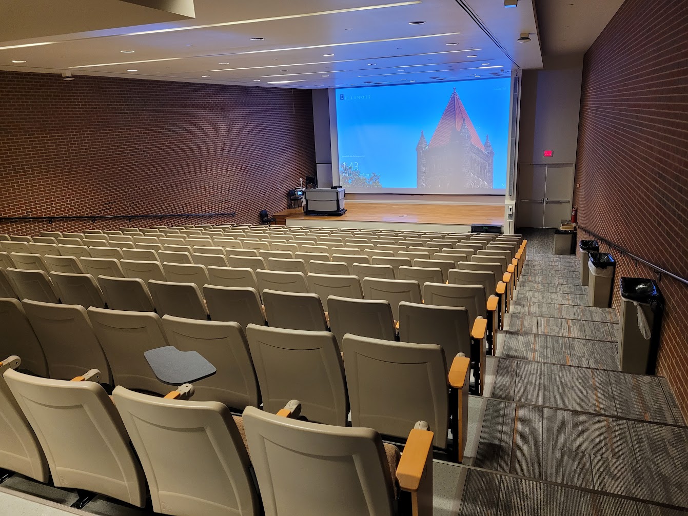 A view of the classroom with theater auditorium seating, and a stage in front.