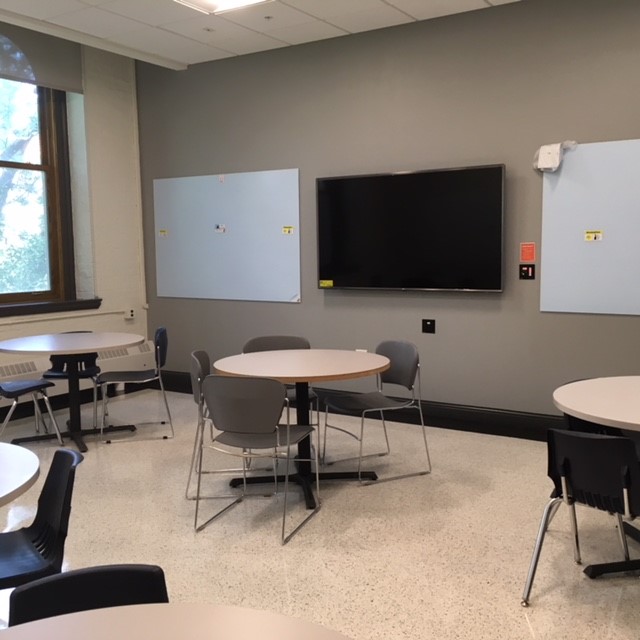 This is a view of the room with student desks, LCD monitor, and white boards.
