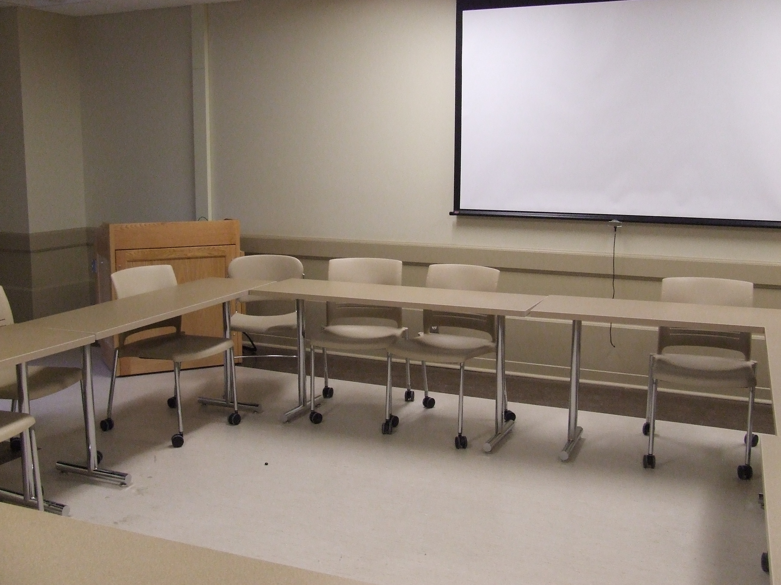 A view of the classroom with movable tables and chairs and instructor table in front.