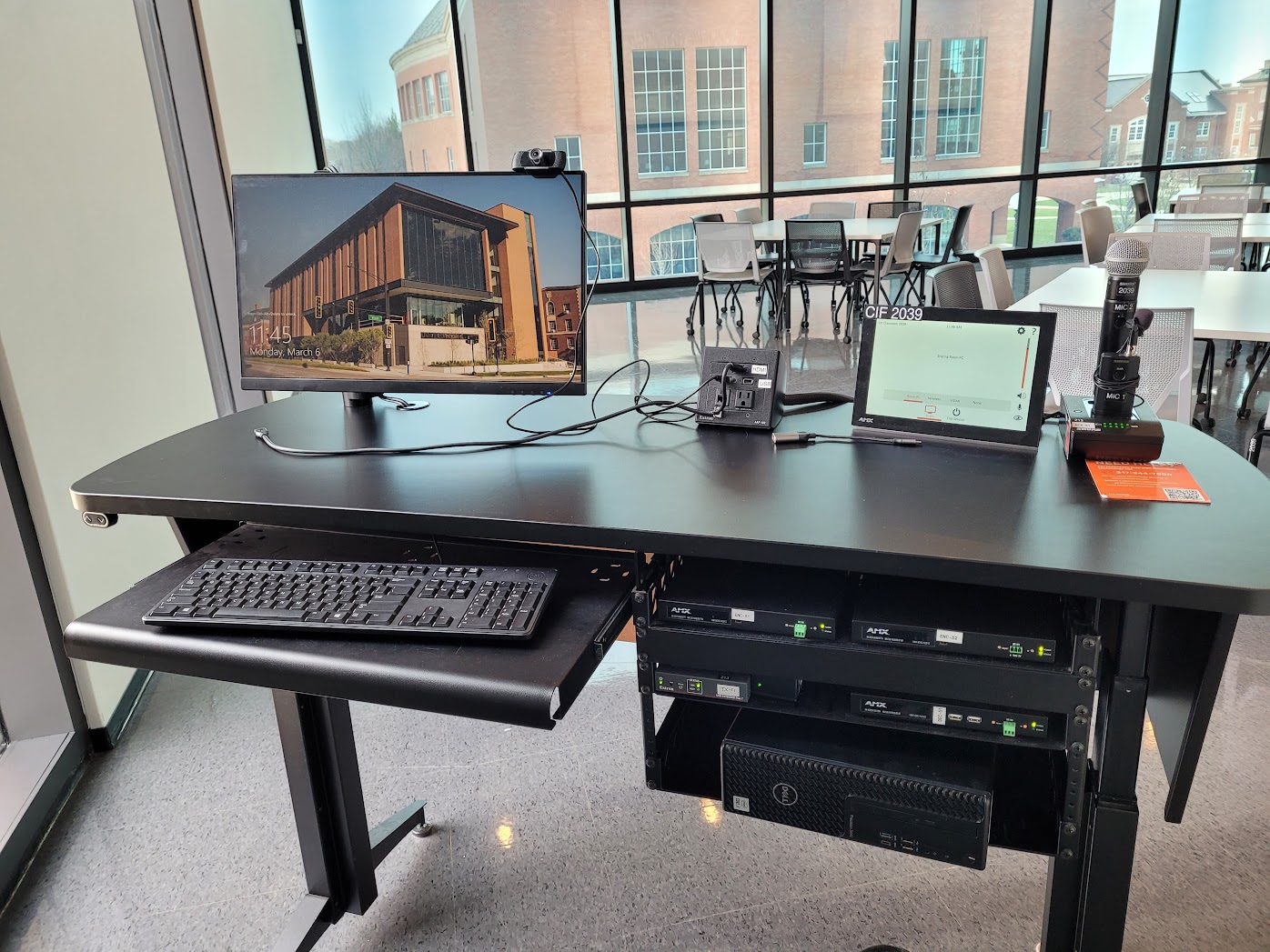The instructor lecture table with the control panel, keyboard, mouse, monitor, and microphone on top, the PC, and sound equipment mounted underneath.