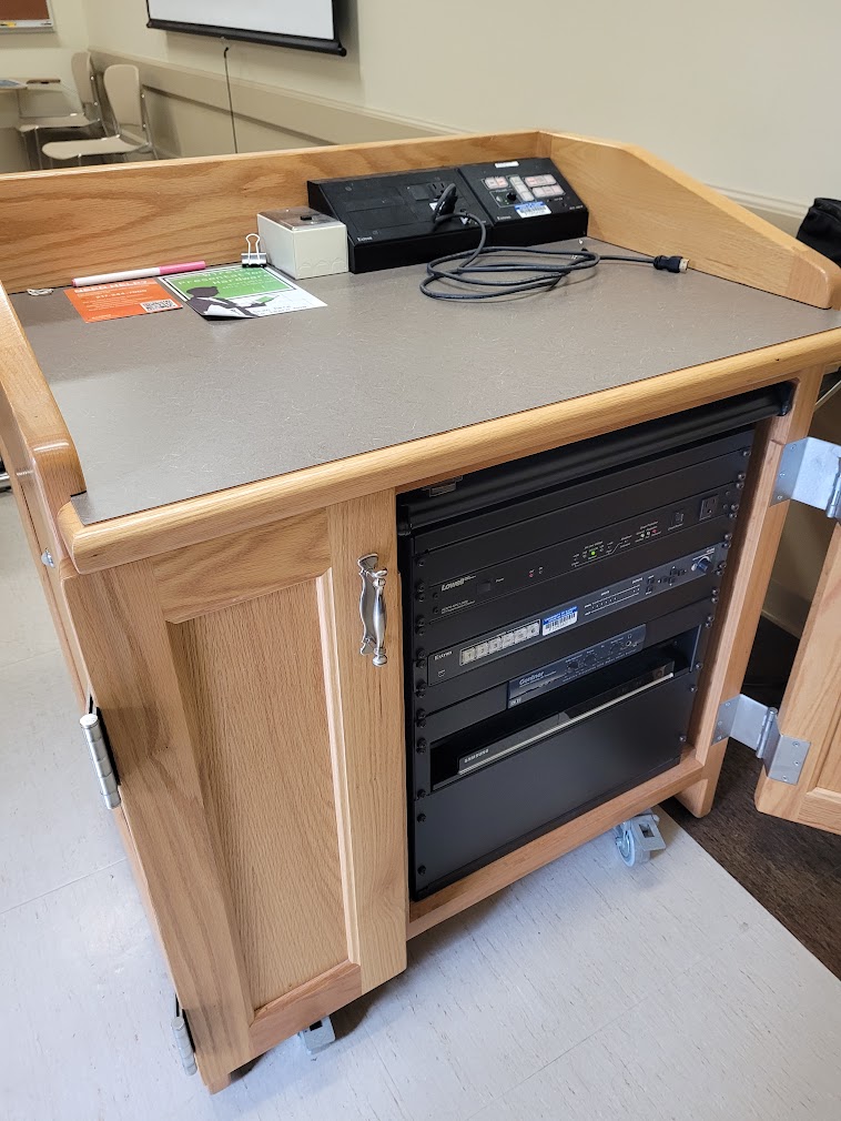 A view of the open cabinet with HDMI input, a push button controller and audio visual rack.