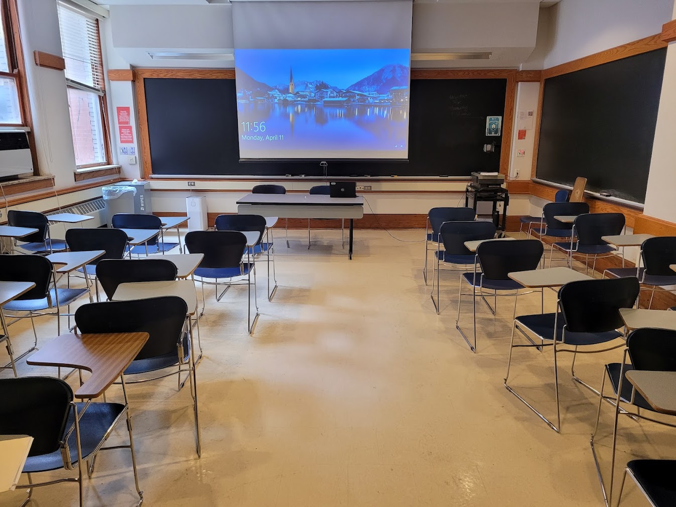 This is a view of the room with student desks, a front lecture table, and a chalkboard.