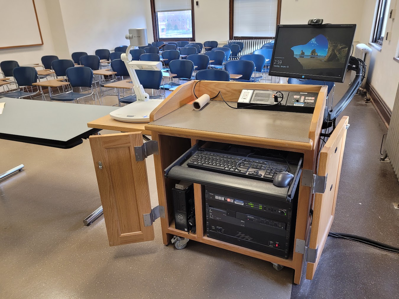 A view of the open cabinet with a computer monitor, HDMI inputs, a push button controller, document camera and audio visual rack.