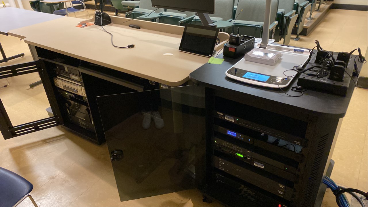 A view of the open cabinet with a computer monitor, HDMI input, document camera, touch panel controller, and audiovisual rack.