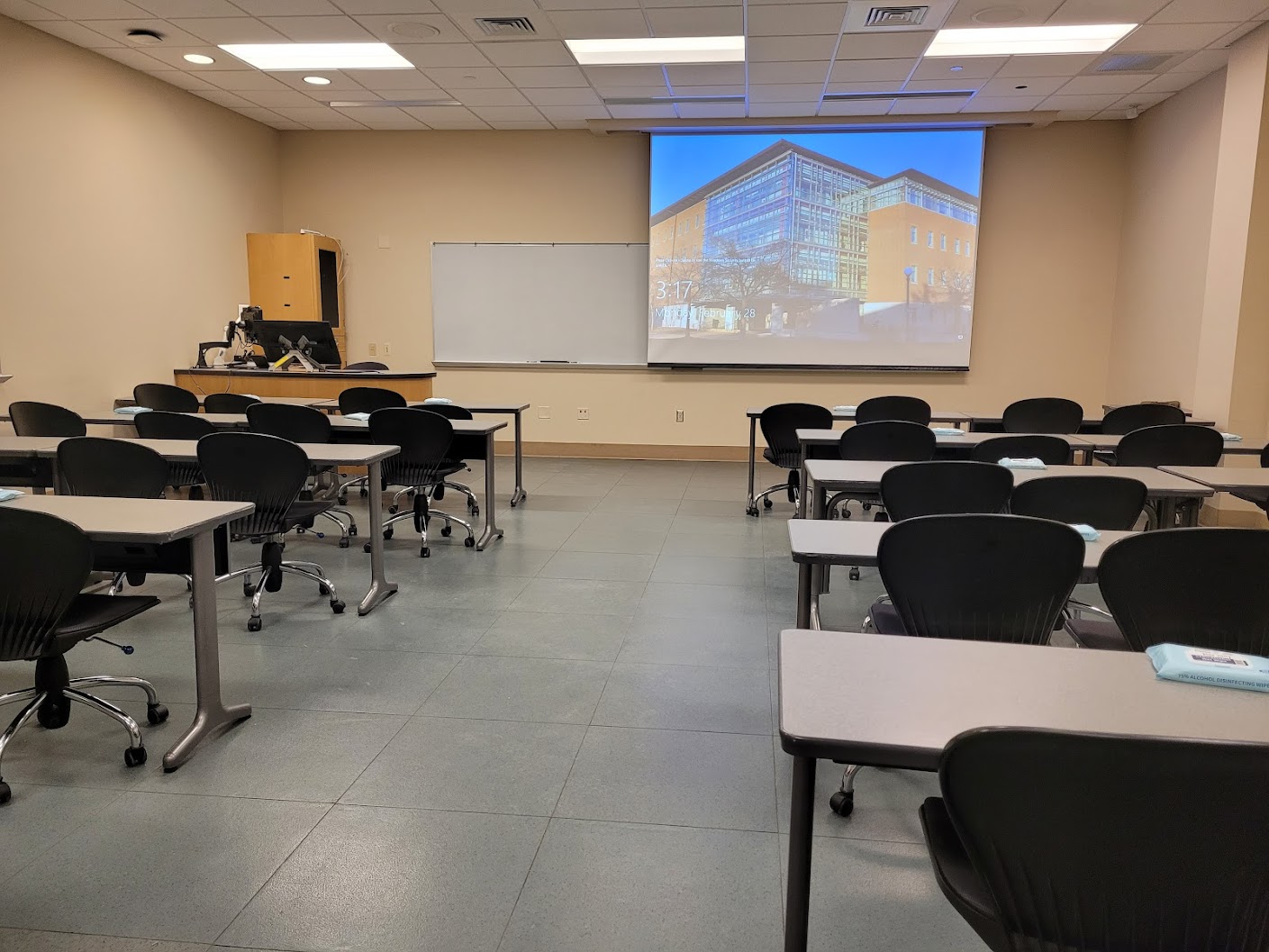 A view of the classroom with movable tables and chairs, white board, and instructor table in front.